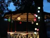 A gazebo decorated with colorful lanterns and string lights at dusk. Podgląd zdjęcia produktu