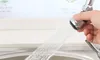 A hand holding a faucet extender over a sink, with water spraying from it. Produktbild-Vorschau