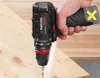A hand holding a cordless drill and drilling into a piece of wood. Produktbild-Vorschau
