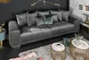 A modern living room scene featuring a large gray sofa with multiple pillows, two round coffee tables, and a fluffy rug. Produktbild-Vorschau