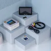 A product display of an AV recorder and its accessories arranged on a series of light blue geometric blocks against a light blue background. Náhled obrázku produktu