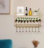 A gold wine rack mounted on a wall, holding wine bottles and wine glasses. A framed picture and a potted plant are on the top shelf. Podgląd zdjęcia produktu