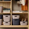 Storage baskets and folded clothes are neatly arranged on wooden shelves in a closet. Produktbild-Vorschau