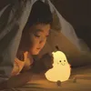 A young boy is lying in bed under a blanket, looking at a pear-shaped night light. Produktbild-Vorschau