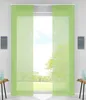 Two green panel curtains are shown hanging in front of a window with a view of trees and a lawn.
