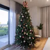 A decorated Christmas tree stands in a modern room with large windows and sheer curtains. Produktbild-Vorschau