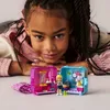 A young girl is lying on her stomach, looking at the camera, with two small LEGO Friends beauty salon playsets in front of her. Náhled obrázku produktu