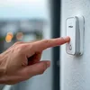 A hand is pressing a doorbell button on a wall. Náhľad obrázku produktu