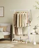 A white garment rack with clothes and accessories is placed next to a bed in a bedroom. Produktbild-Vorschau