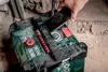 A hand is placing a smartphone on top of a green and black battery-powered radio. Podgląd zdjęcia produktu