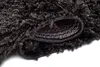 A close-up view of a dark gray shaggy rug, showing the texture of the fibers and the underside of the rug. Produktbild-Vorschau