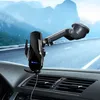 A black car phone mount with wireless charging is attached to the dashboard of a car, with a blurred road and mountains in the background. Produktbild-Vorschau