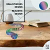 A colorful 3D printed snake toy is coiled on a wooden table, with an open book in the background. Voir les images du produit