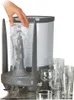 A hand is shown placing a glass into a glass washing device, with several clean glasses in the foreground. Podgląd zdjęcia produktu