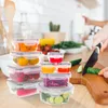 A kitchen scene with food storage containers and a person preparing food. Produktbild-Vorschau
