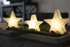 Three illuminated star-shaped lights are arranged on a tray with pine branches and small decorative balls. Produktbild-Vorschau