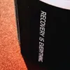 A close-up of a black product with white text on it, resting on an orange surface. Produktbild-Vorschau