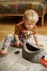 A young boy is playing with toys on a rug in a room. Produktbild-Vorschau