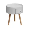 A white round bedside table with a drawer and three wooden legs, isolated on a white background. Anteprima dell’immagine prodotto
