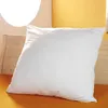 A white pillow is placed on an orange surface, with a wooden headboard and a yellow wall in the background. Produktbild-Vorschau