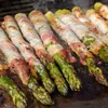 Asparagus wrapped in bacon is being grilled. Podgląd zdjęcia produktu