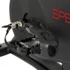 A close-up view of the pedal and flywheel of a black stationary bicycle. Produktbild-Vorschau
