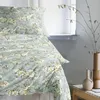 A close-up view of a bed with floral patterned bedding, placed near a window with decorative branches in vases. Produktbild-Vorschau