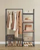 A clothing rack and shelving unit filled with neutral-toned clothing and accessories, displayed against a plain wall. Náhled obrázku produktu