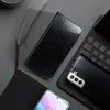 A black flip phone case is shown on a dark gray surface, next to a keyboard and a feather quill. Produktbild-Vorschau