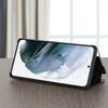 A black phone case is displayed on a wooden table, propped up by its own stand. Produktbild-Vorschau