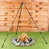 A tripod stand with a chain and hook is set up over a small campfire in a backyard setting. Produktbild-Vorschau