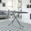 An ironing board is set up in a modern living room with a sofa and shelves in the background. Voir les images du produit