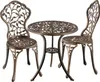 A bistro set with a round table and two chairs, made of ornate cast metal with a leaf motif.