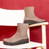 Two brown boots are displayed on a white chair against a red background. Produktbild-Vorschau