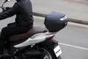 A person riding a scooter with a top case attached to the back. Anteprima dell’immagine prodotto