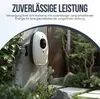 A white charging device mounted on a wall in an outdoor garden setting. Produktbild-Vorschau