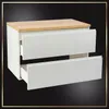A white cabinet with two drawers and a wooden top, set against a black background with a decorative border. Produktbild-Vorschau