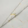 A close-up view of a white blanket with a gold marble pattern. Anteprima dell’immagine prodotto