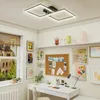 A modern room with a desk, shelves, and artwork, featuring a geometric ceiling light. Produktbild-Vorschau