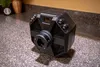 A black Thrustmaster steering wheel base sits on a speckled countertop. Produktbild-Vorschau