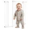 A baby stands in front of a white baby gate. Voir les images du produit