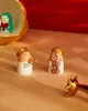 Two small angel figurines playing musical instruments, with a larger golden bowl in the background containing another angel figurine. Produktbild-Vorschau