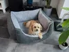 A dog is resting in a dog bed in a living room. Produktbild-Vorschau