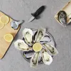 A top-down view of an oyster serving set laid out on a grey fabric surface, including oysters, lemons, an oyster knife, a lemon squeezer, and a serving tray. Voir les images du produit