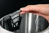 A hand holding a filter over the opening of a stainless steel kettle. Produktbild-Vorschau