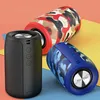 Three portable Bluetooth speakers with camouflage patterns are arranged diagonally on a multi-colored background. Produktbild-Vorschau