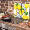 A kitchen counter with a stovetop, a frying pan, and ingredients for cooking, with a decorative glass splashback featuring lemons. Produktbild-Vorschau