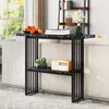 A narrow console table with a marble-look top and black metal frame, placed behind a sofa. It holds decorative items like oranges, books, a radio, and plants. Produktbild-Vorschau