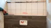 A person is using a laser distance measurer to mark a line on a tiled wall. Produktbild-Vorschau