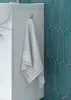 A close-up of a bathroom cabinet with a towel hanging on a hook, next to teal tiles. Náhled obrázku produktu